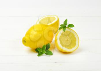 whole and halved lemons on white wooden background