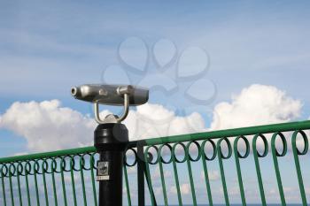 Coin-operated spy viewing machine against cloudy sky