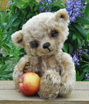Handmade, the sewed toy: teddy bear Lucky with an apple among flowers