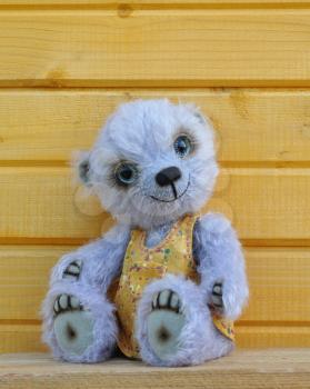 Handmade, the sewed toy: teddy-bear Chupa before a wooden wall