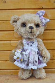 Handmade, the sewed toy: teddy-bear Lucky before a wooden wall