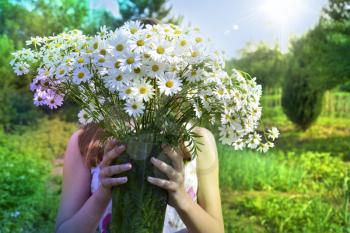  girl with a bouquet of white field chamomiles on a summer sunny day