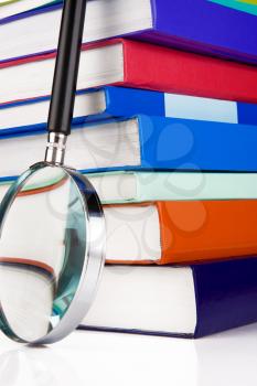 pile of books and magnifying glass isolated on white background