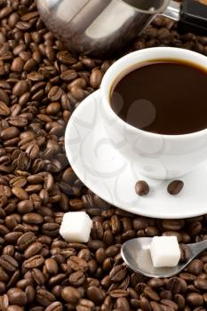 cup of coffee and spoon on roasted beans as background