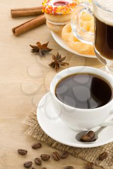 cup of coffee with beans and cakes on wood background