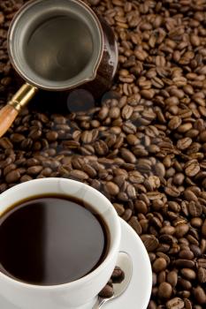 cup of coffee and pot on roasted beans as background