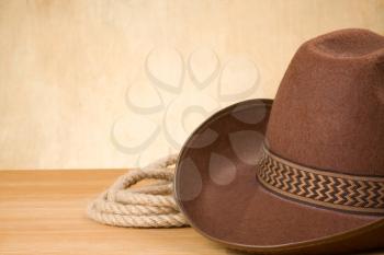 brown cowboy hat and rope on wood texture background