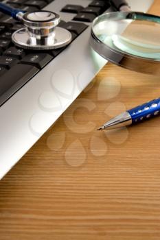 stethoscope, magnifying glass and pen on keyboard