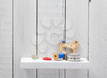 sewing tools and accessories on shelf wooden background