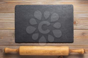 slate stone and rolling pin at rustic wooden plank board table background, top view