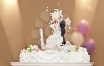 Pie with figures of the groom and the bride on a wedding table.
