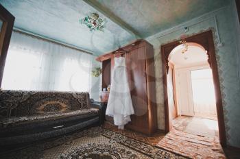 The wedding dress hangs on a door.