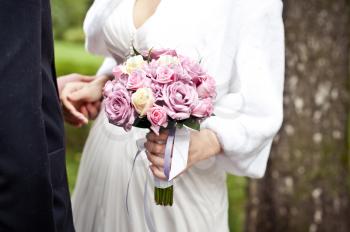 Bouquet from roses for the bride. Pink roses and white dress of the bride
