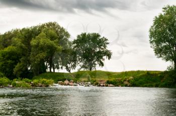 Trees on the river bank. Cloudy weather, river rift, trees ashore.
