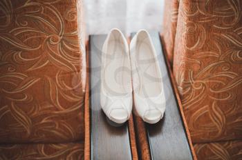 White shoes of the bride lie on a chair.