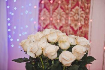 White roses in a bouquet against garlands.