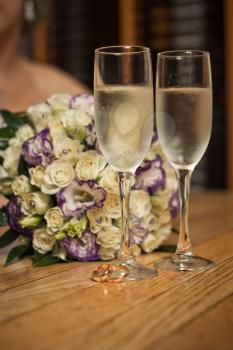 Glasses with champagne and a bouquet on a table.