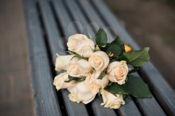 Bouquet from white roses on a bench.