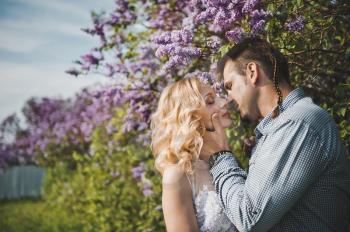 Newly-married couple among lilac bushes.