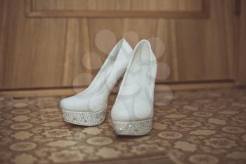White beautiful shoes on a high sole stand on the floor rooms.
