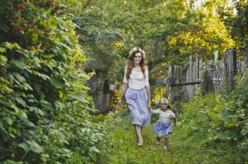 Mother with her little daughter walking in the garden.