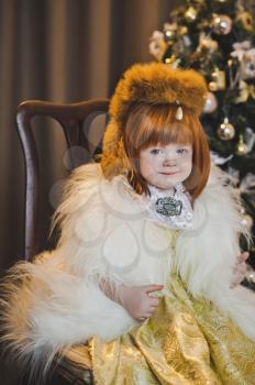 Little Princess in a fur coat around the Christmas tree.