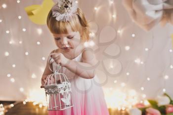 A little girl with a white bird in the cage.