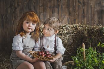 A girl and a boy holding a dish with Easter eggs.