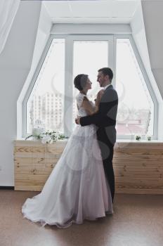 Husband and wife embracing against the window.