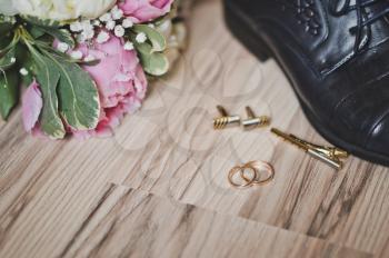 Wedding ring on the floor surrounded by flowers and shoes.