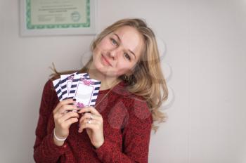 Beautiful girl in a sweater holding in his hand the gift tickets.