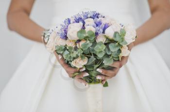 Purple beige bouquet in hands of bride in a white dress.