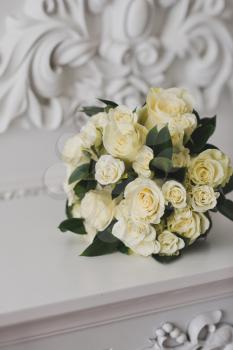 A neat bouquet of beige roses lying on a white table.