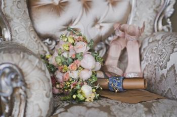 Bouquet and brides shoes on a luxurious chair.