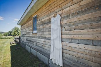 Wedding dress on a hanger against a Bar wall.