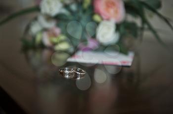 Wedding rings on the table with a bouquet.