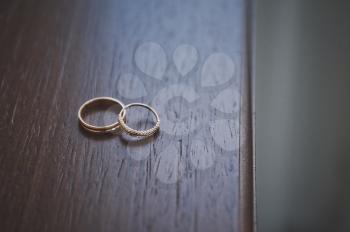 Wedding rings on a dark wooden table.