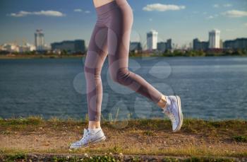 running legs of a woman against the backdrop of the city and the river