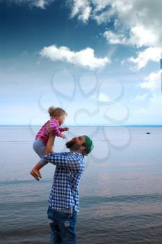Dad or father and his baby daughter hugging on a boat or ferry in the sea on a cool summer day