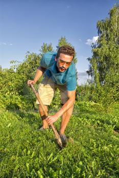 young man with a shovel digging a vegetable garden