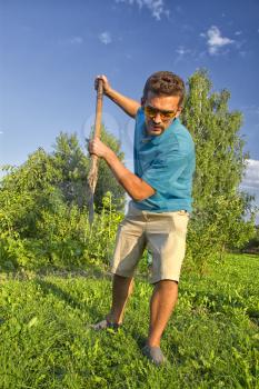 young man with a shovel digging a vegetable garden
