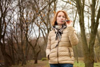 girl with the electronic cigarette in the park autumn