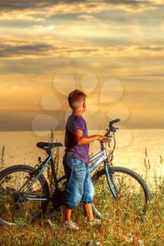 boy on a bicycle near the sea in the evening at sunset. summer vacation
