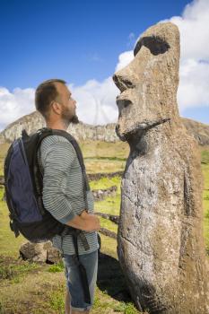man traveler stands with a backpack on the background of Easter Island statues