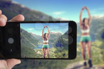 blogger takes a smartphone girl on the edge of the mountain