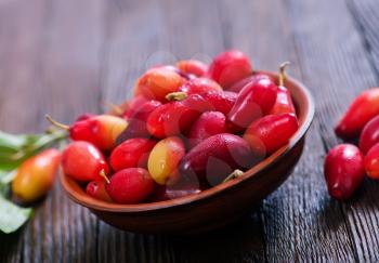 cornelian cherry berry in bowl on wooden background