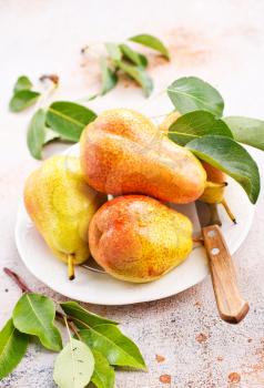 fresh pears on plate and on a table