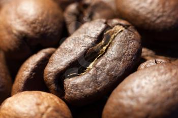 Brown roasted coffee bean in heap of coffee beans close-up macro photo natural food background, selective focue, shallow depth of field.