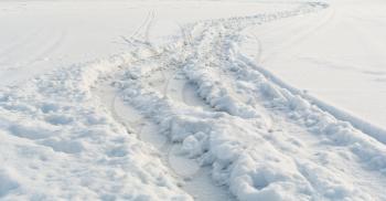 Car tire tracks on white winter snow field close-up perspective view