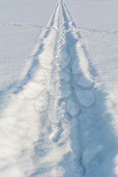 Snow track with footprints on white winter snow field perspective view